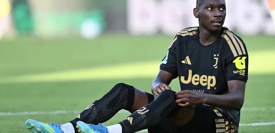 Juventus player sitting on the field, adjusting socks