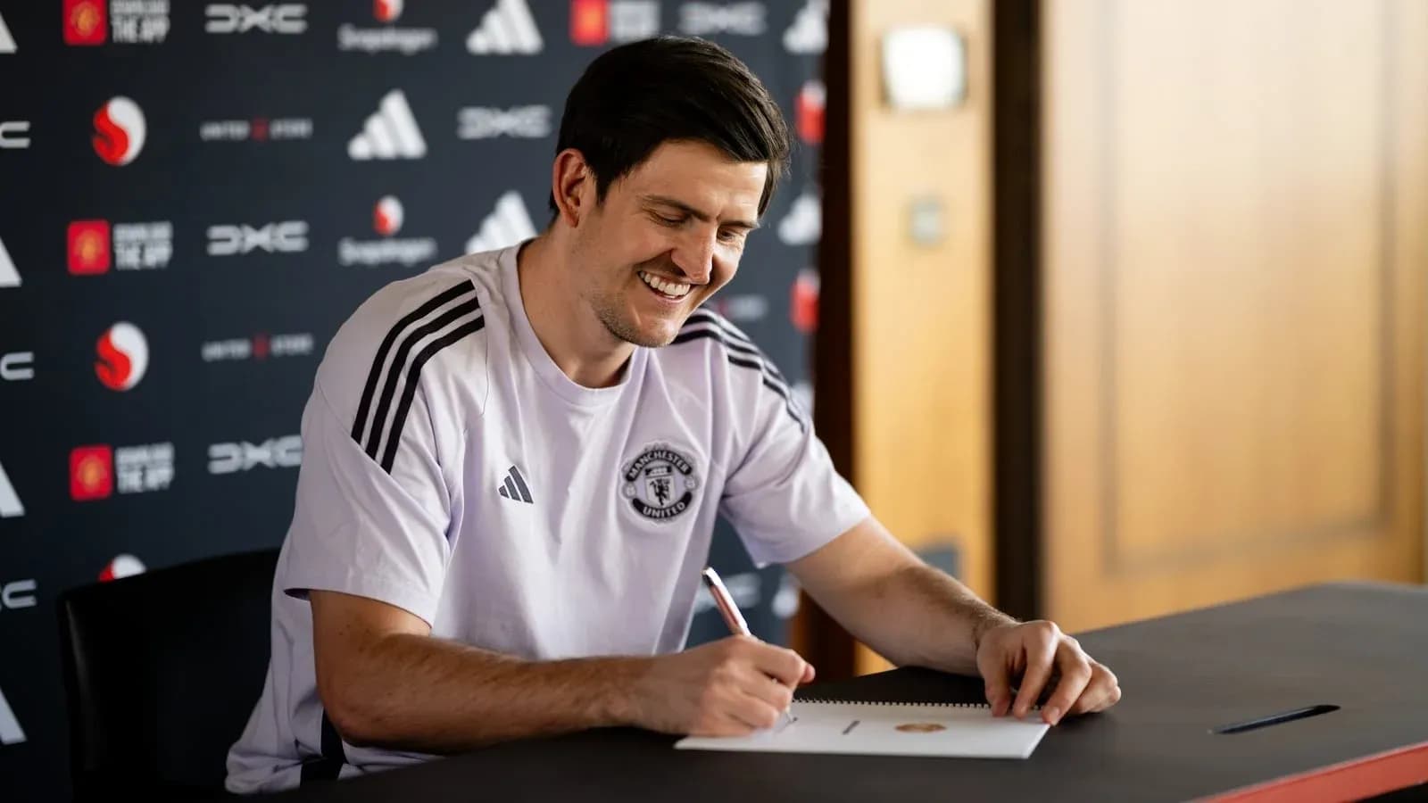Player signing contract at press conference table
