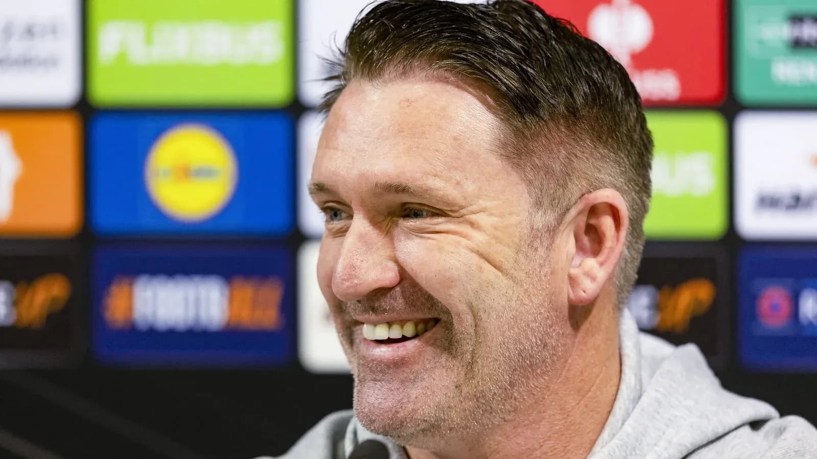 Man smiling during a press conference setup