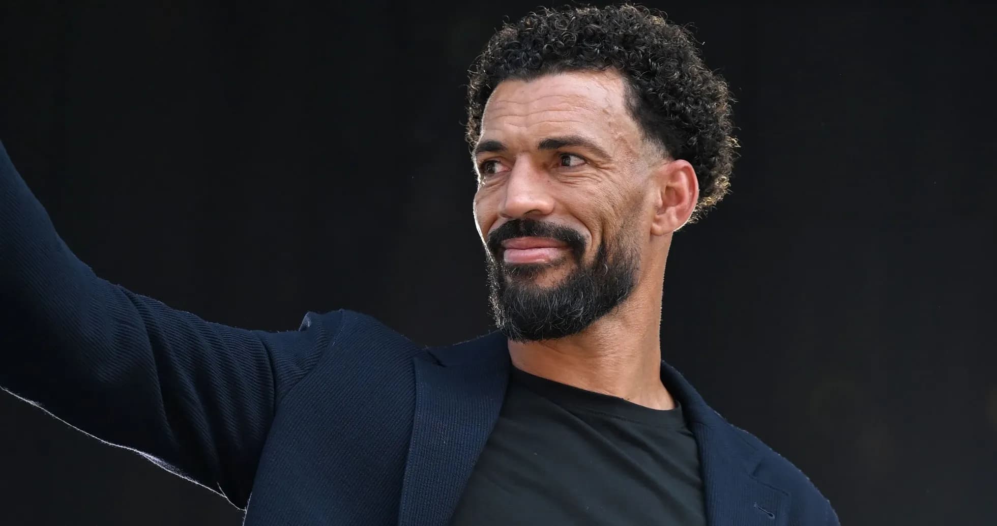 Man in a blazer waving during an event
