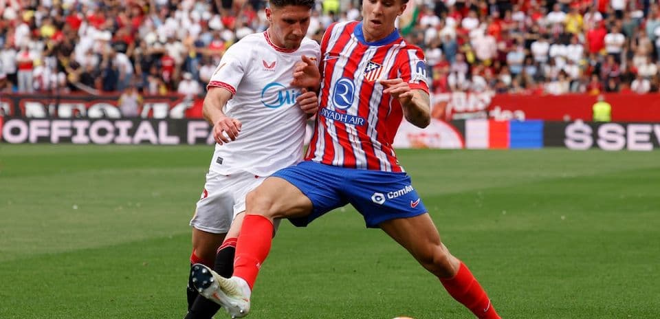 Sevilla player challenging Atletico Madrid opponent