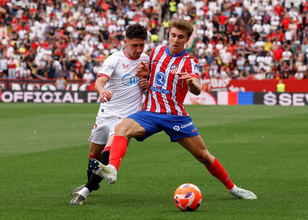 Sevilla player challenging Atletico Madrid opponent