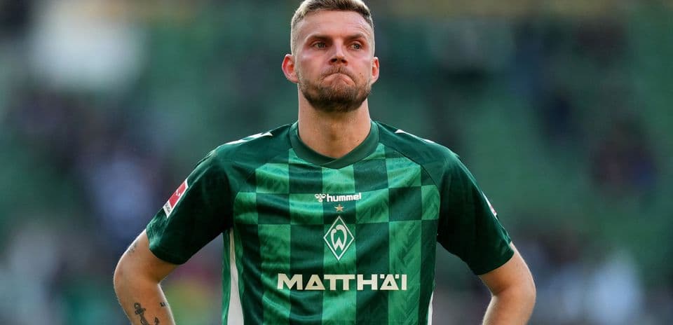 Player in green jersey stands with serious expression