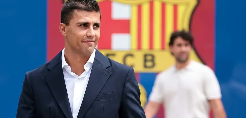 Man in suit standing in front of Barcelona logo