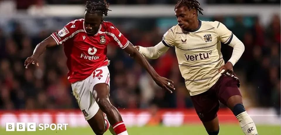 Player in red racing against opponent in cream jersey