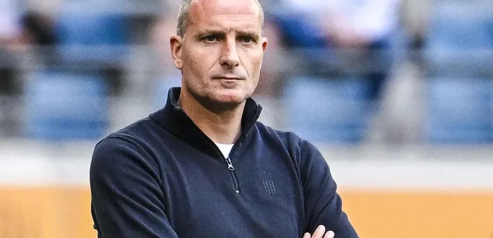 Coach standing with arms crossed during match