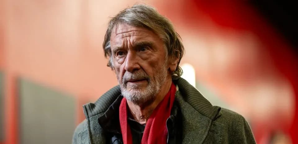 Man in gray coat with red scarf indoors