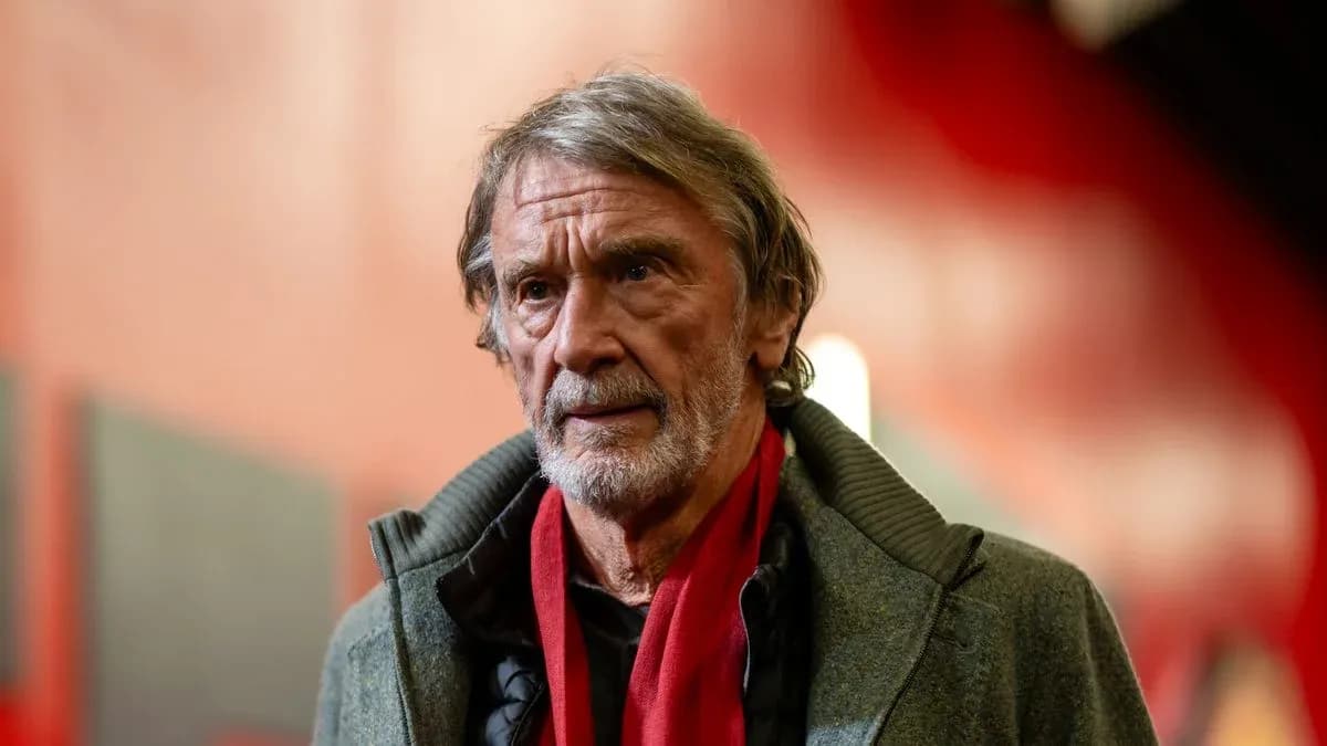 Man in gray coat with red scarf indoors