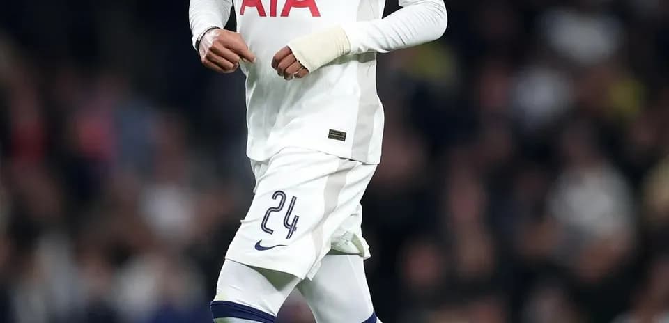 Player in Tottenham kit dribbling football on pitch