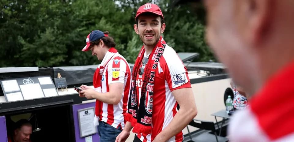 Fans wearing Stoke City shirts and scarves outdoors