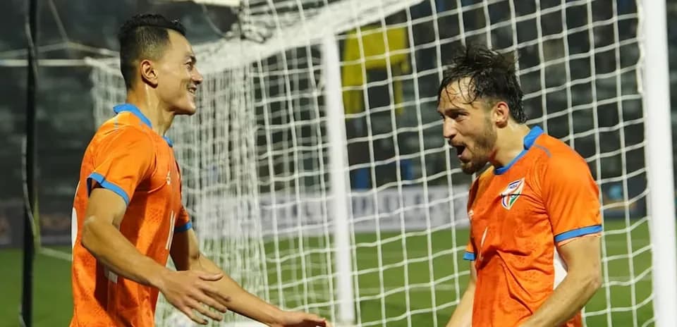 Two players celebrating a goal in orange jerseys
