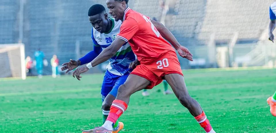 Two soccer players competing for the ball on field