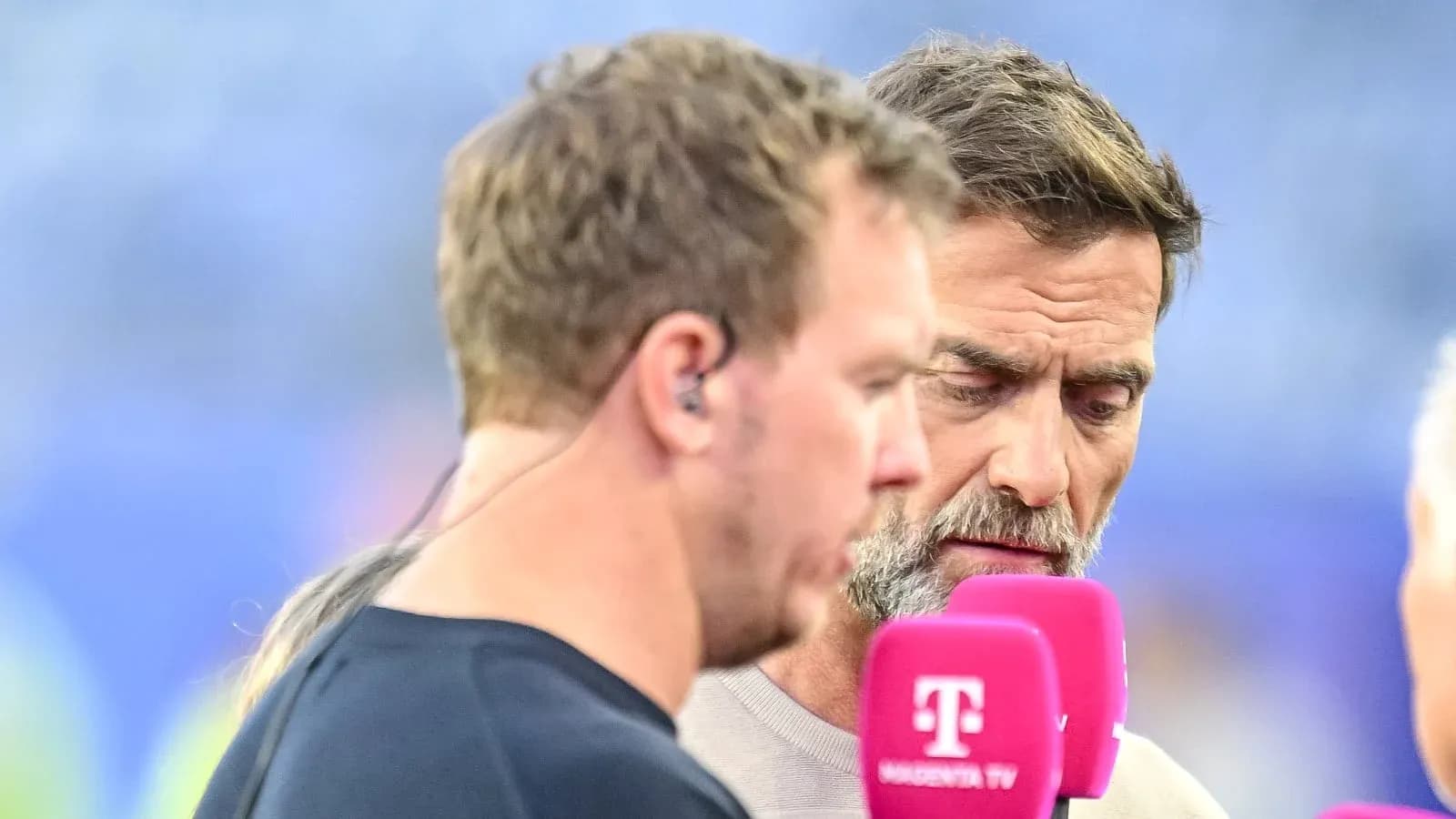 Two men speaking into microphones during broadcast