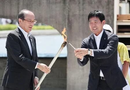 Two officials passing a lit torch during ceremony