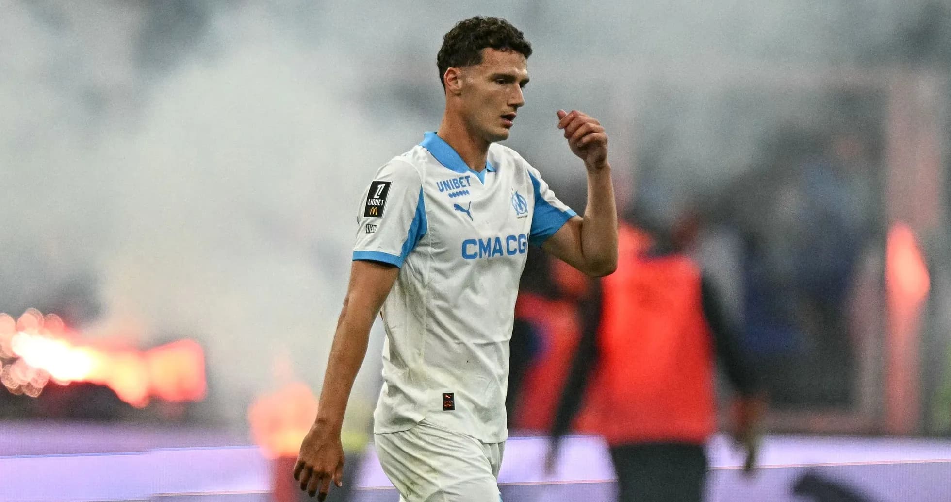 Player walking off the field with smoke in background