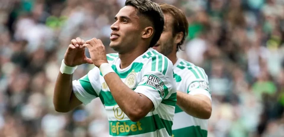 Player celebrating goal with heart gesture in stadium