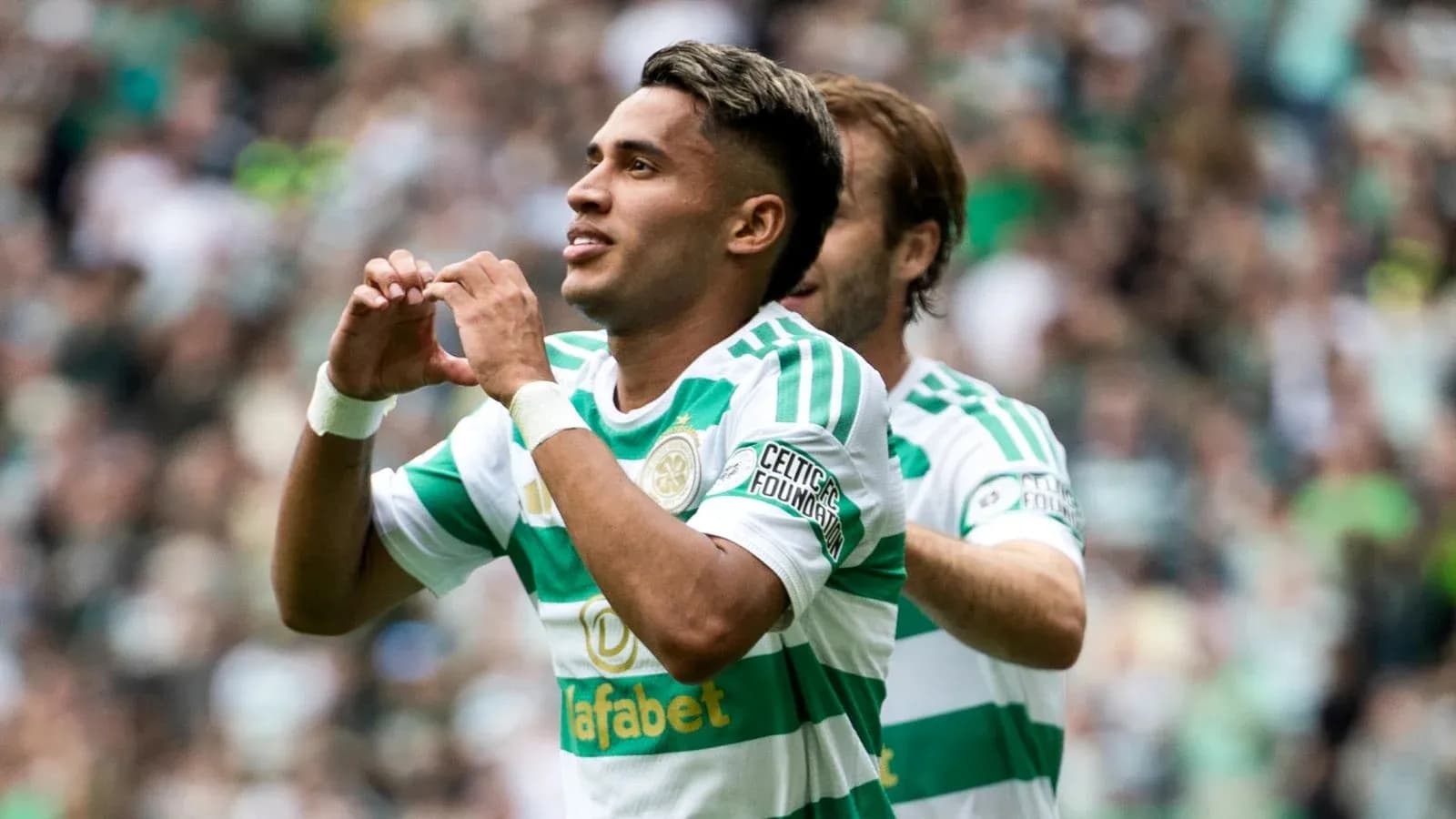 Player celebrating goal with heart gesture in stadium