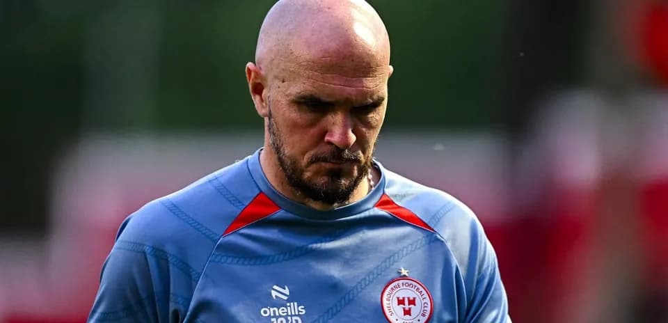 Player walking on training pitch, wearing club jersey