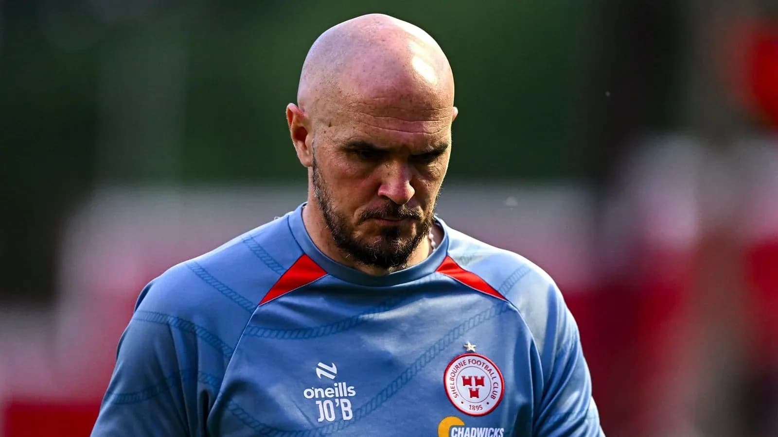 Player walking on training pitch, wearing club jersey