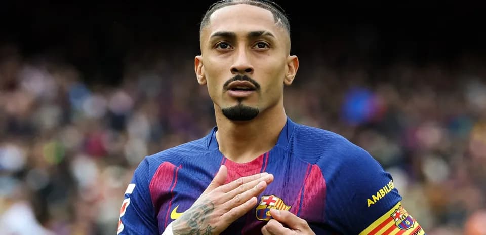 Player gesturing towards FC Barcelona badge on jersey