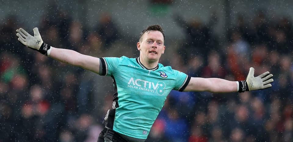 Goalkeeper celebrating with arms outstretched in rain