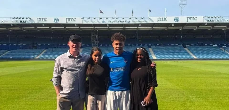 Four people posing on the football pitch