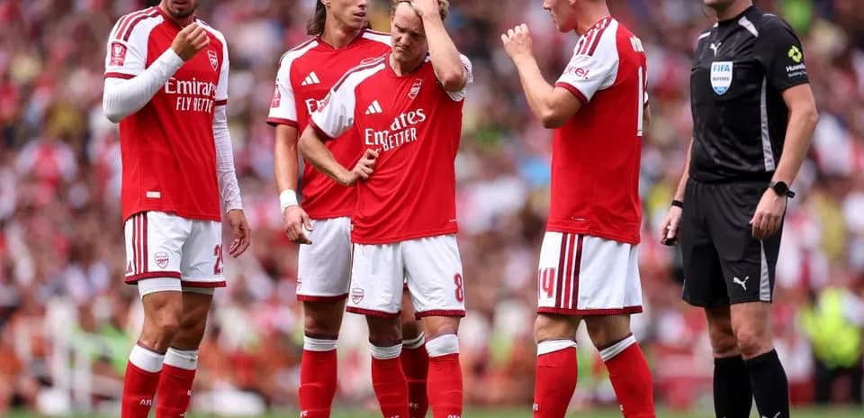 Arsenal players discussing strategy with referee