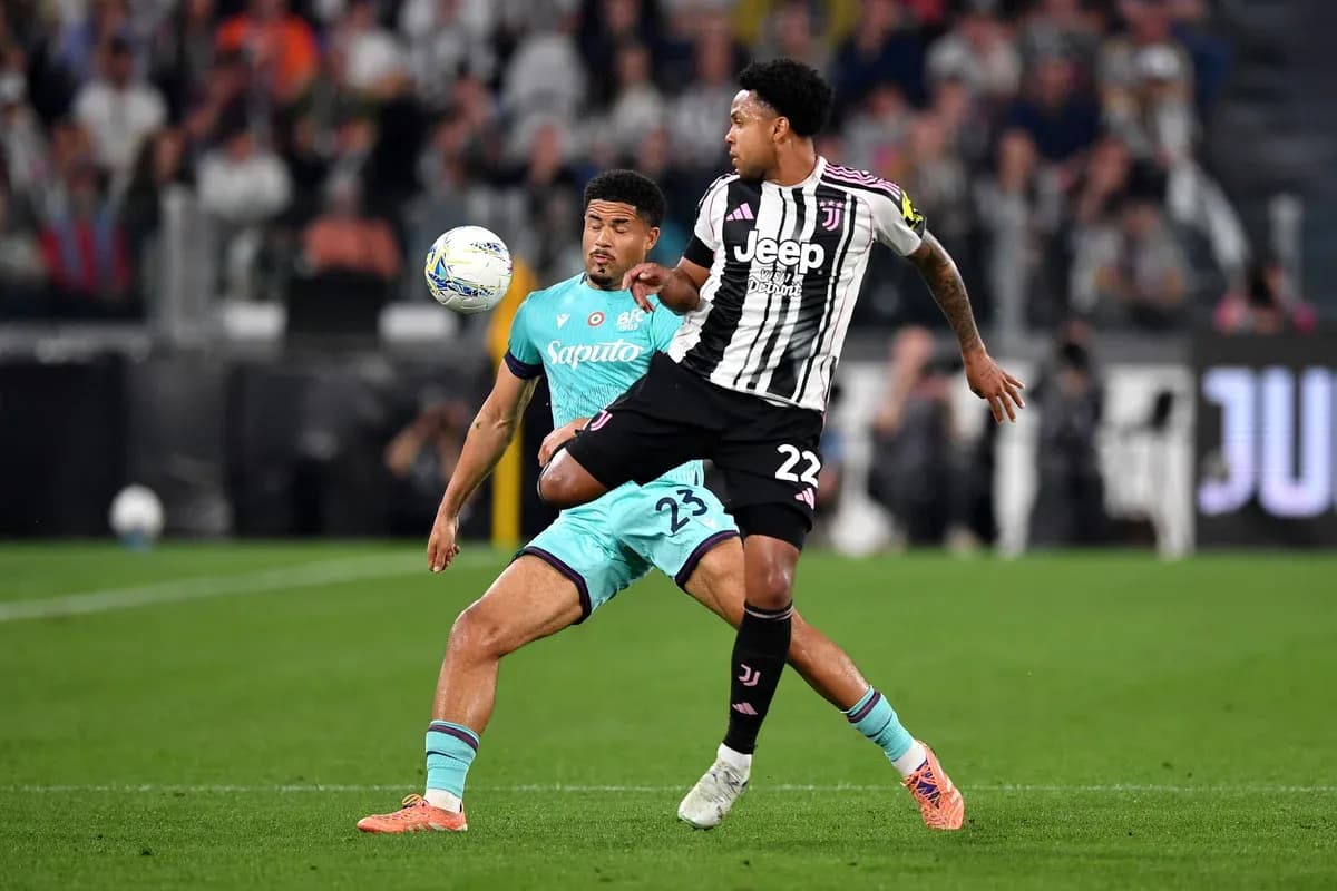 Juventus player challenging Bologna defender for the ball