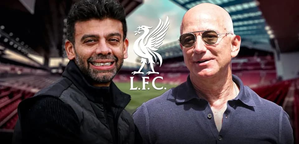 Two men posing at Liverpool FC stadium backdrop