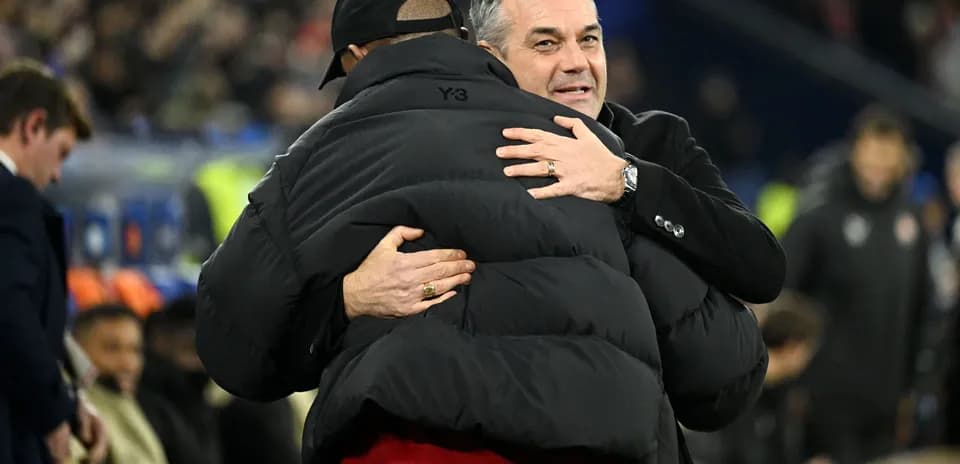 Two coaches embracing on the sidelines after match