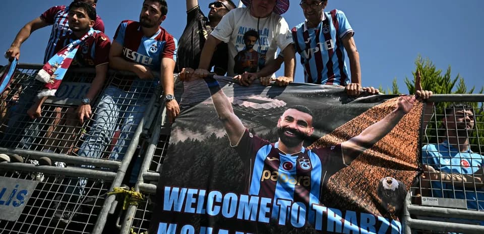 Fans holding welcome banner for player in stadium