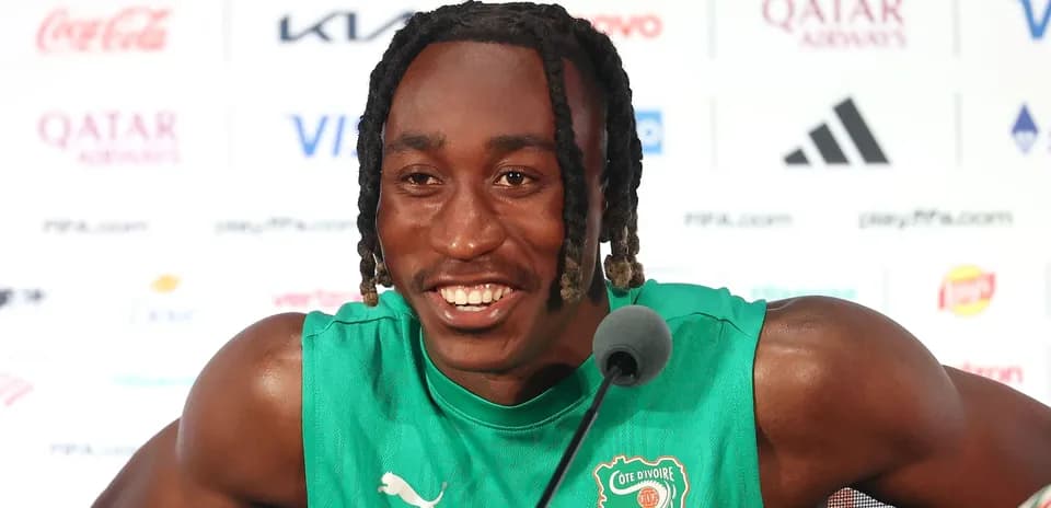 Player speaking at press conference wearing green jersey
