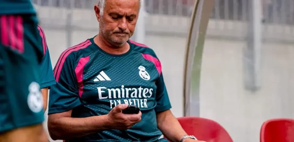 Manager sitting on bench checking phone during match