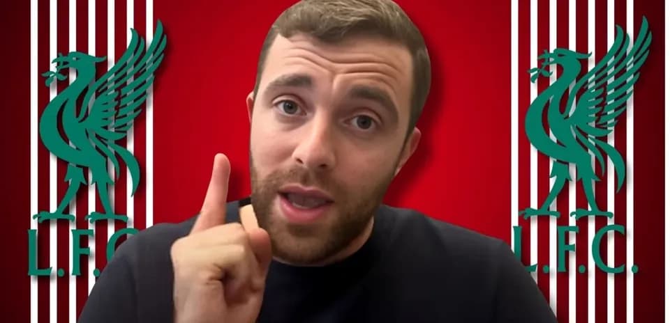 Person gesturing with finger in front of Liverpool FC logo