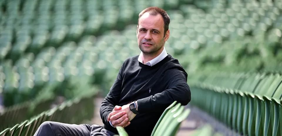 Man sitting on stadium seats, posing for photo
