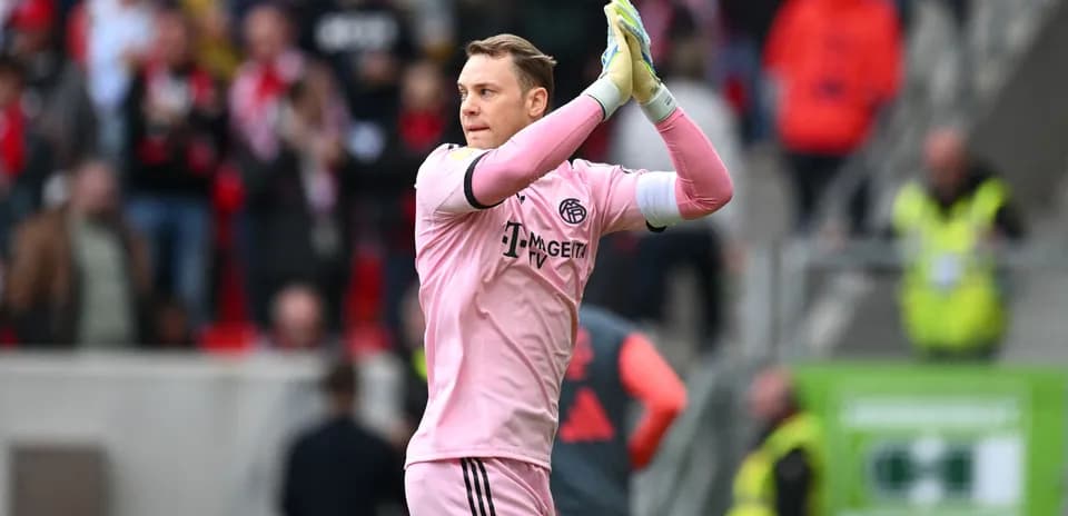 Goalkeeper in pink kit applauding fans after match