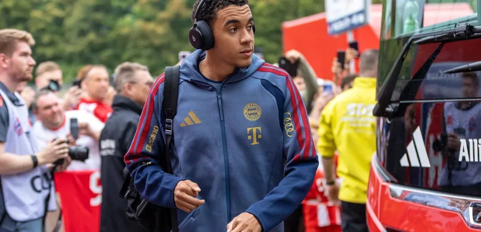 Player arriving at stadium wearing headphones and team jacket