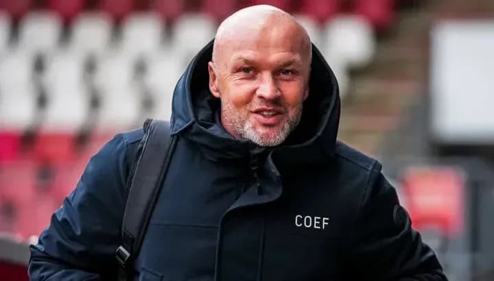 Man in a coat smiling while entering stadium