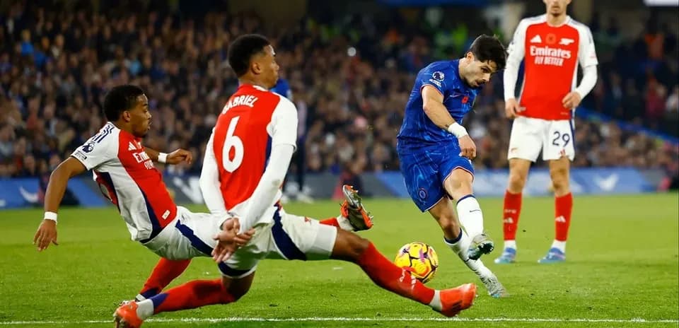 Chelsea player shooting on goal against Arsenal defenders