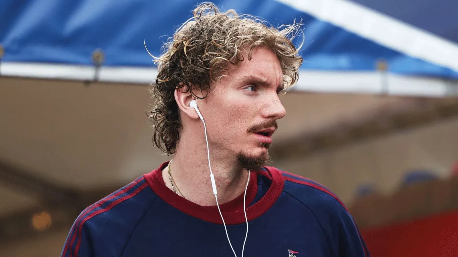 Athlete wearing headphones, walking in casual attire