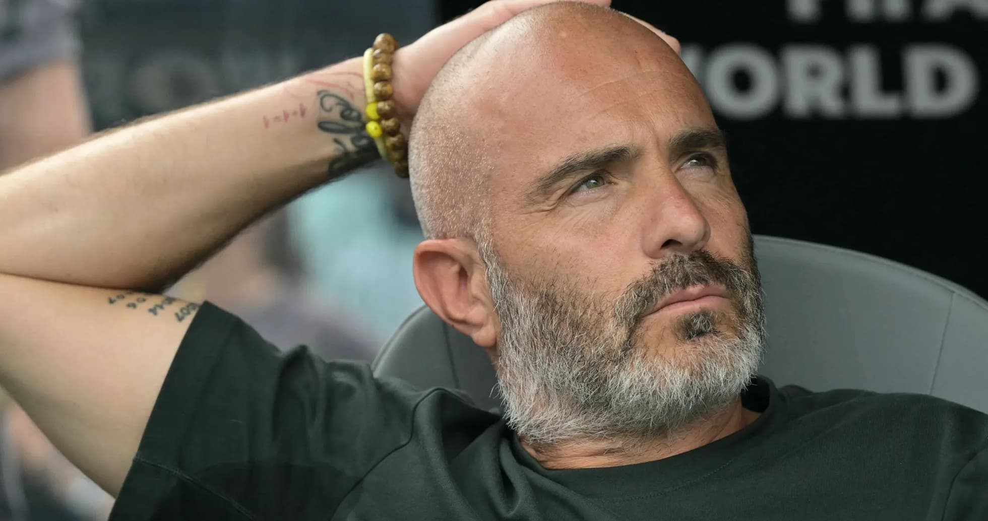 Coach seated, hand on head during match