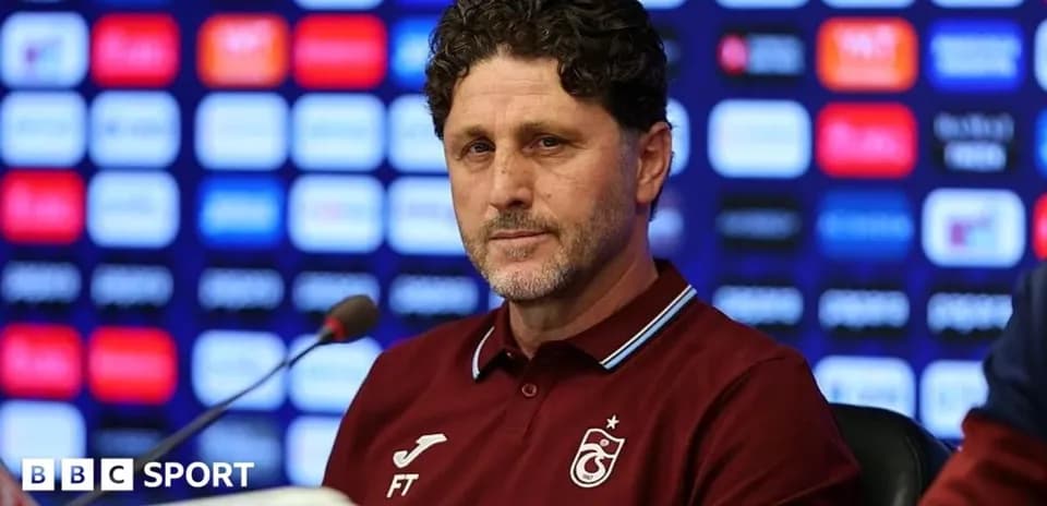 Coach speaking at a press conference with backdrop
