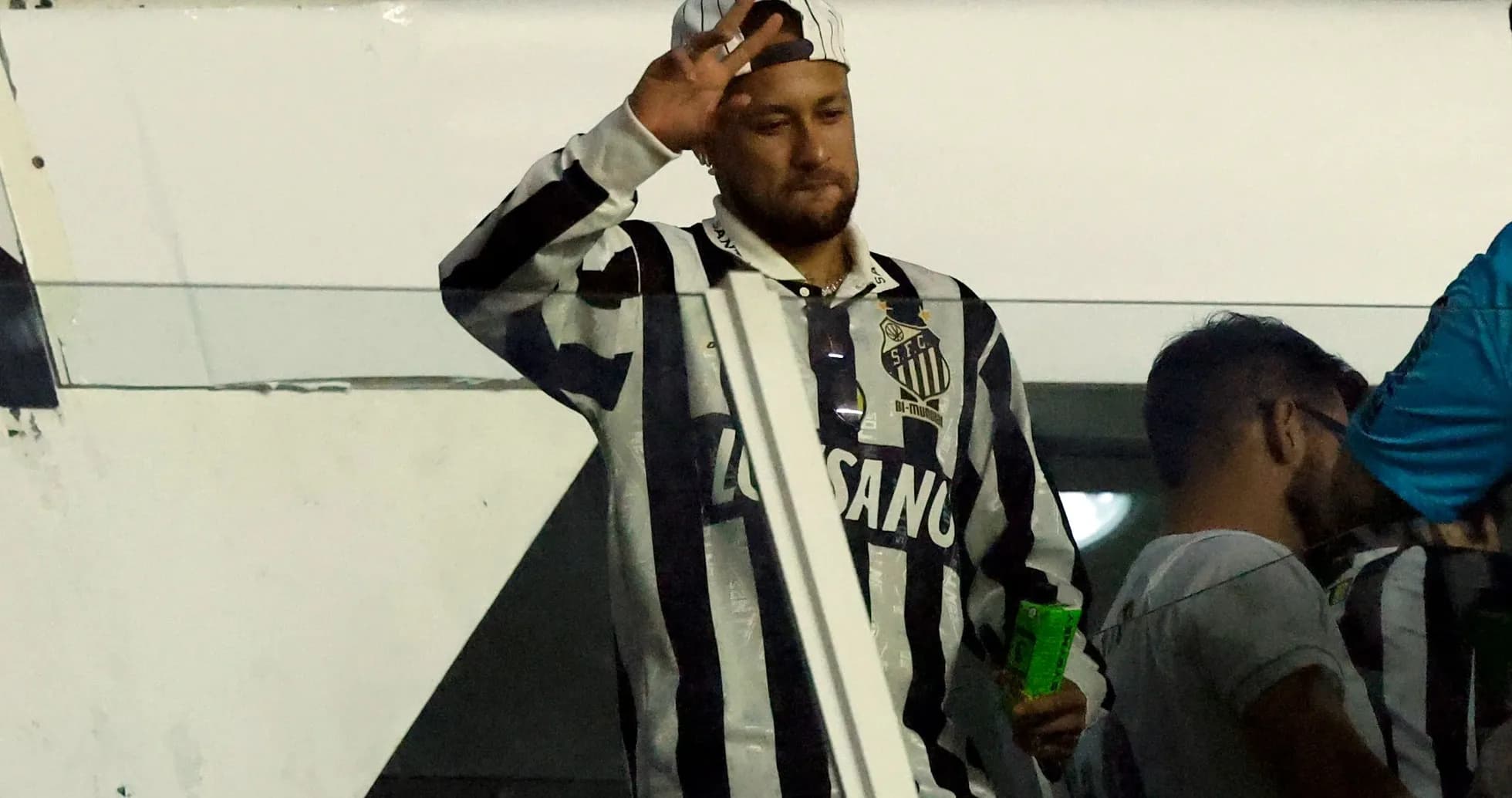Fan waving in Santos FC jersey at stadium