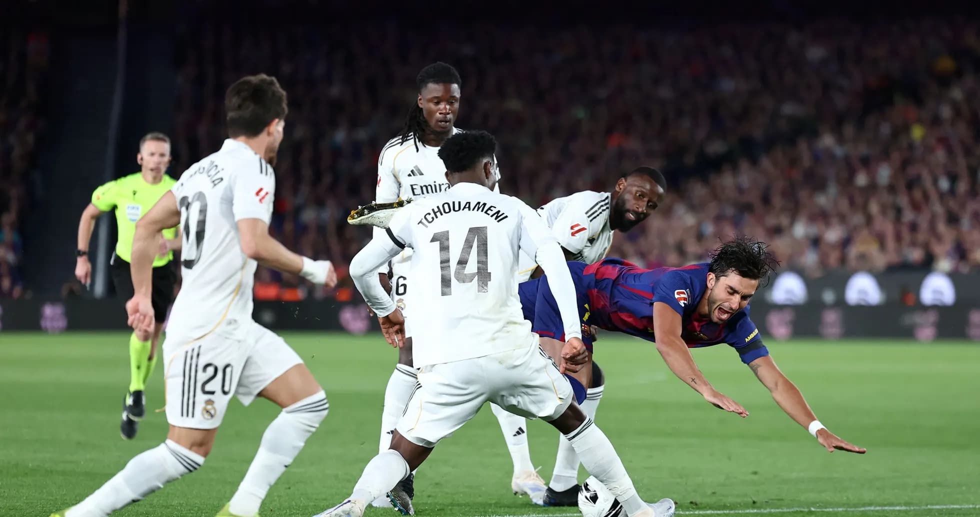 Barcelona player falling amid Real Madrid defenders