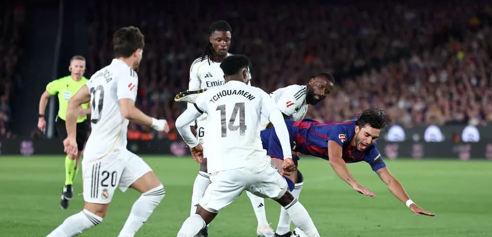 Barcelona player falling amid Real Madrid defenders