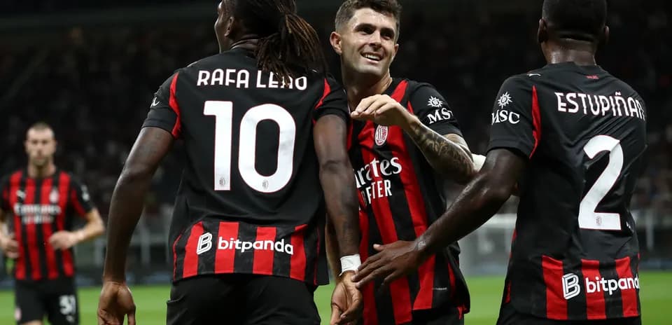Players celebrating a goal in black and red jerseys