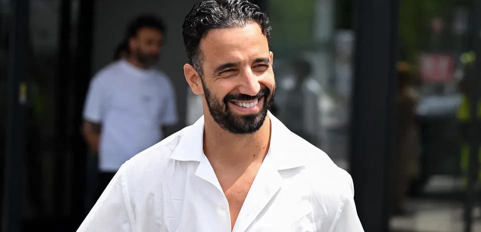 Man in white shirt smiling outside a building