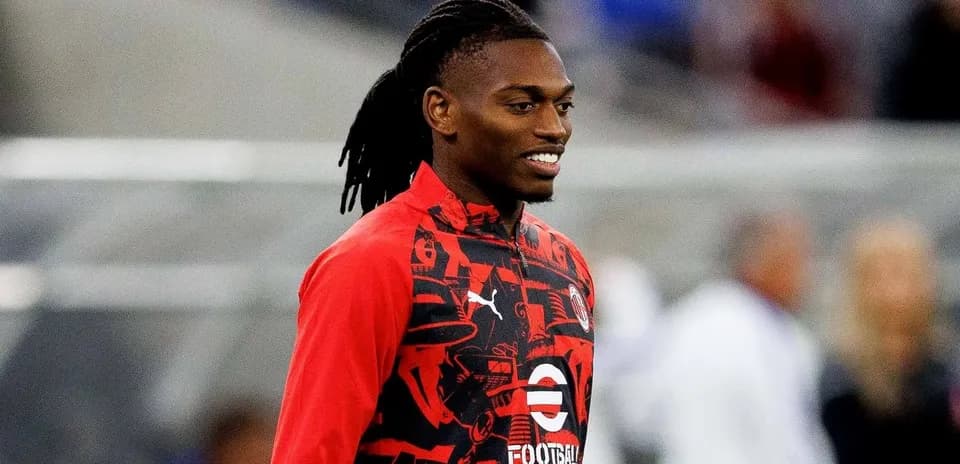 Player smiling while wearing red training jacket