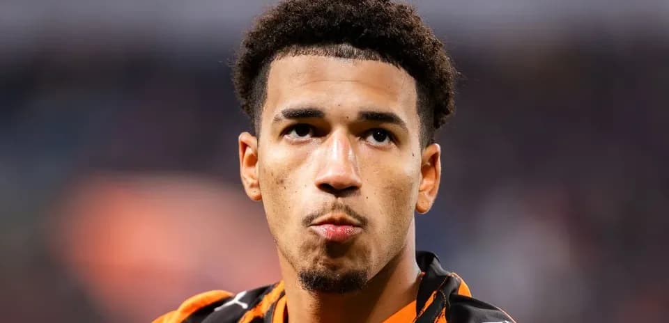 Athlete in orange jersey looking thoughtfully at camera