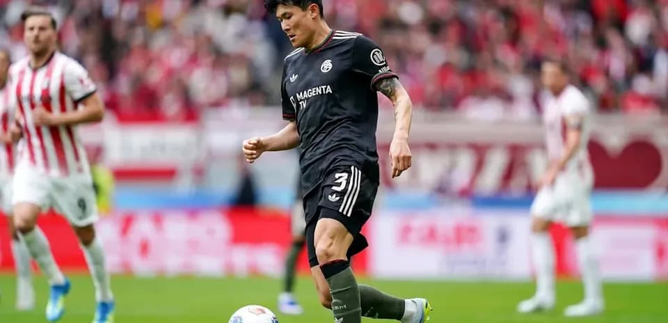 Player in black uniform dribbling the ball on field